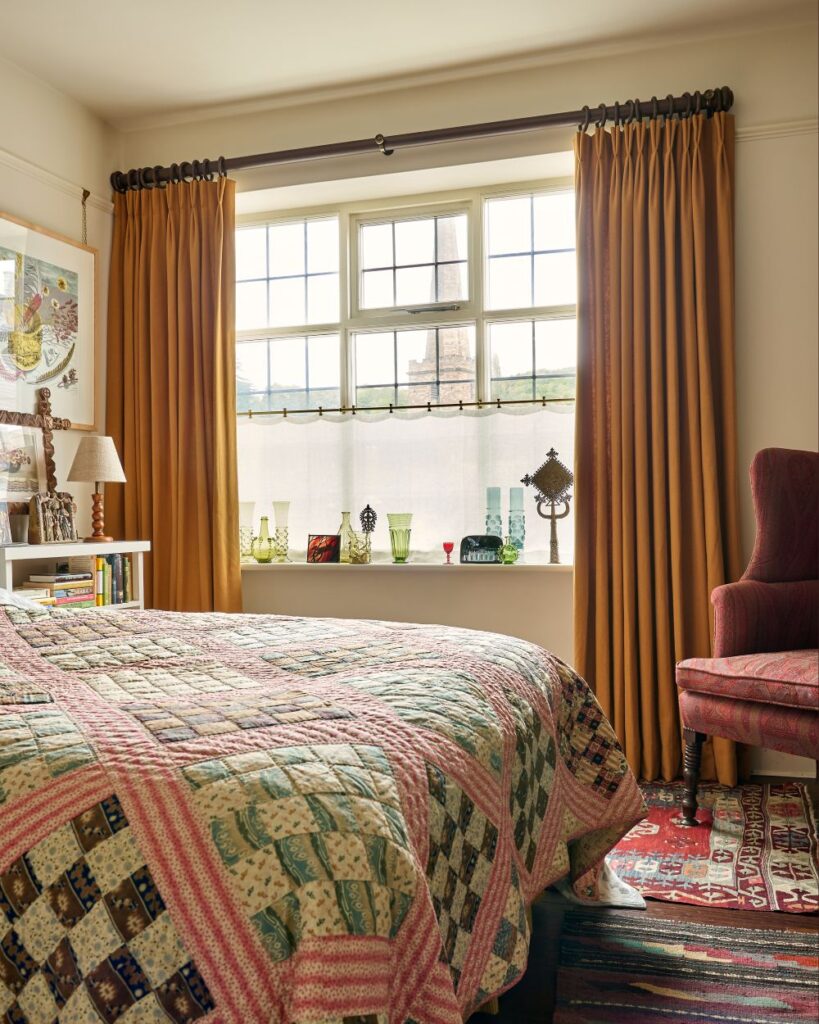 A classic bedroom with double pleat linen curtains and a patchwork quilt