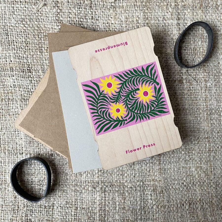 An opened pocket-sized flower press showing cardboard layers