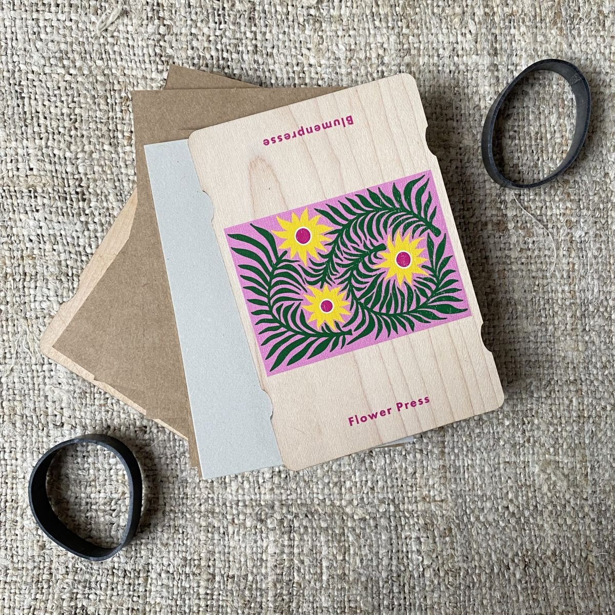 An opened pocket-sized flower press showing cardboard layers