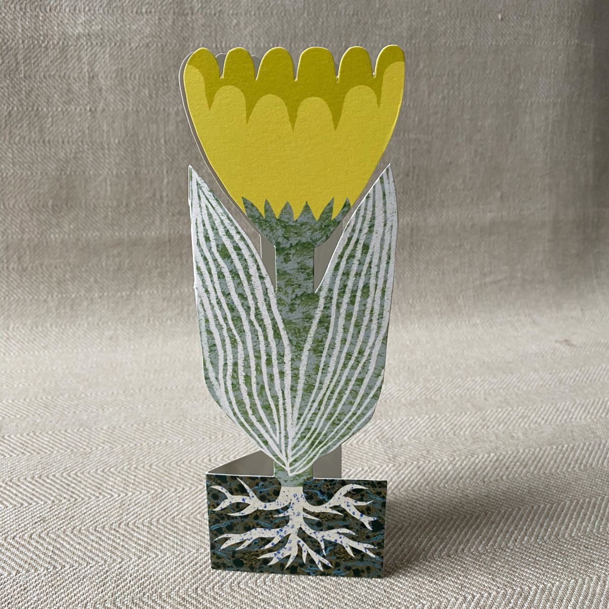 Upright yellow tulip shaped greetings card on a neutral background