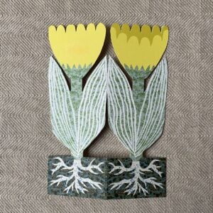 Splayed yellow tulip shaped greetings card on a neutral background