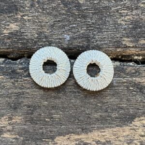 Silver cog earrings on a wooden background