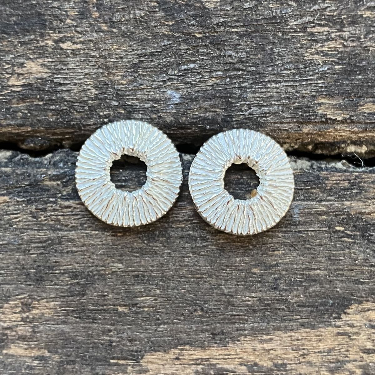 Silver cog earrings on a wooden background