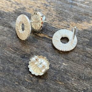 Silver cog earrings on a wooden background