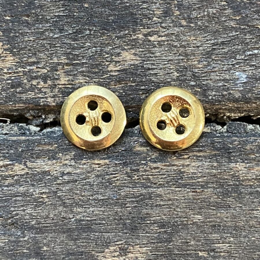 Gold plated button earrings on a wooden background