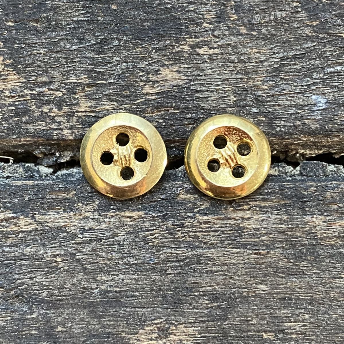 Gold plated button earrings on a wooden background