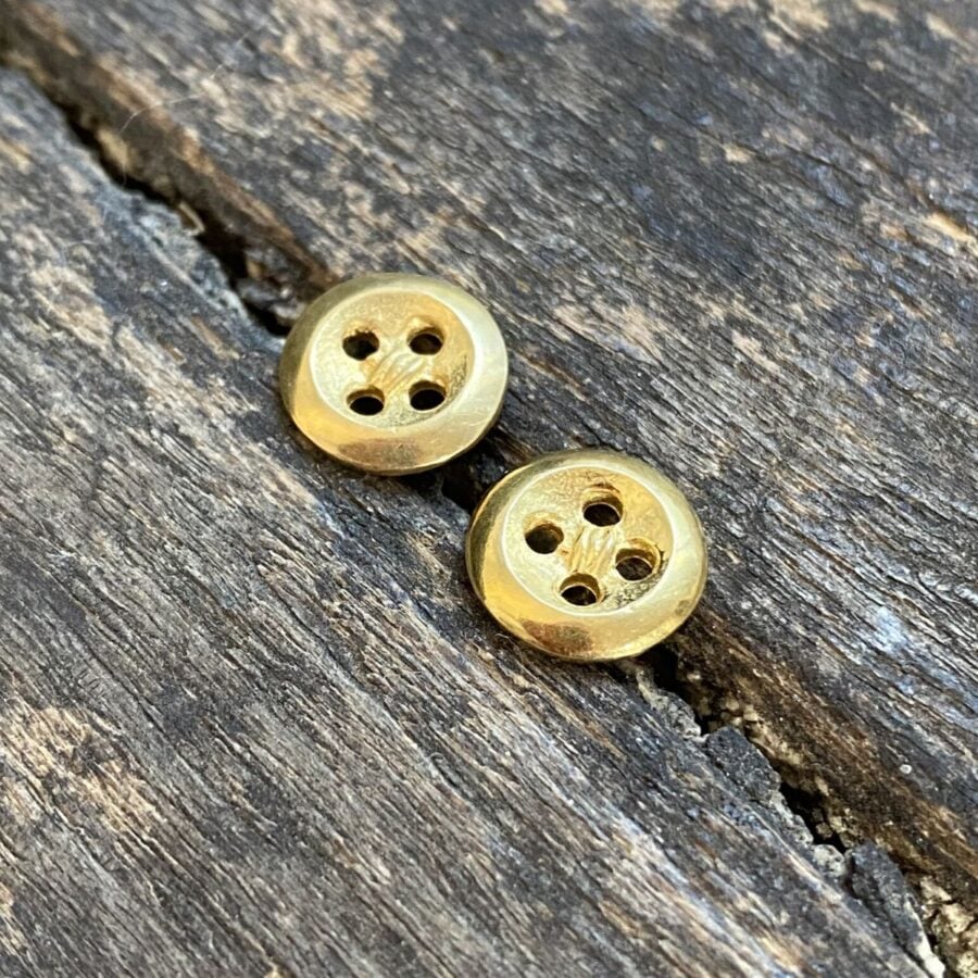 Gold plated button earrings on a wooden background