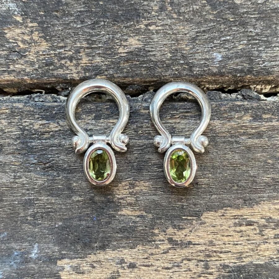Silver drop earrings with peridot centres on a wooden background