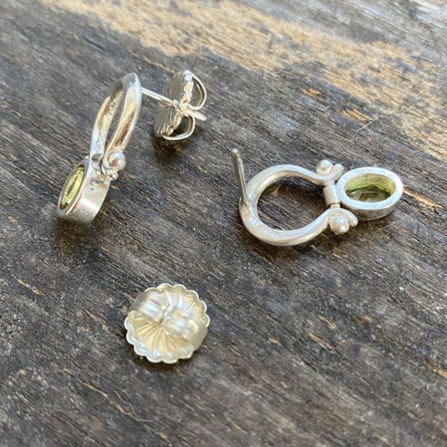 Silver drop earrings with peridot centres on a wooden background