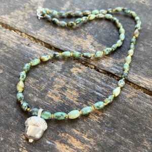 African turquoise gemstone necklace by Clare de la Torre on a wooden background