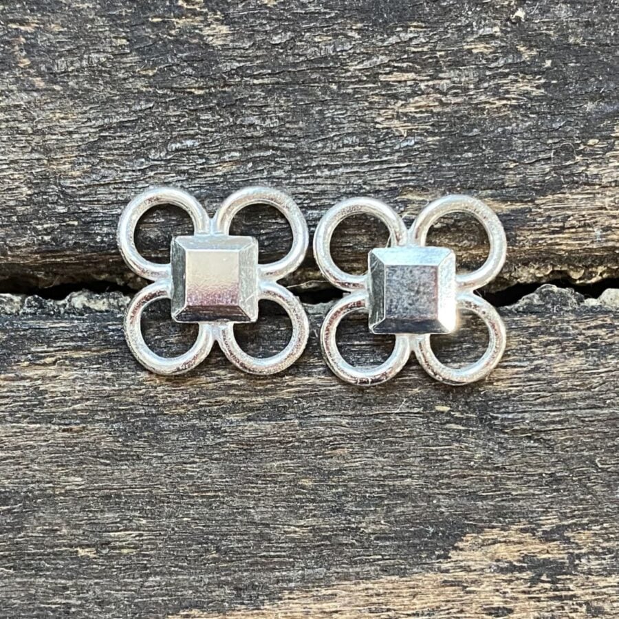 Silver quatrefoil earrings on a wooden background