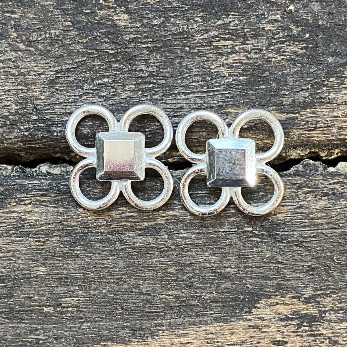 Silver quatrefoil earrings on a wooden background