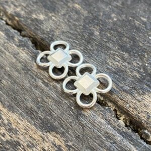 Silver quatrefoil earrings on a wooden background