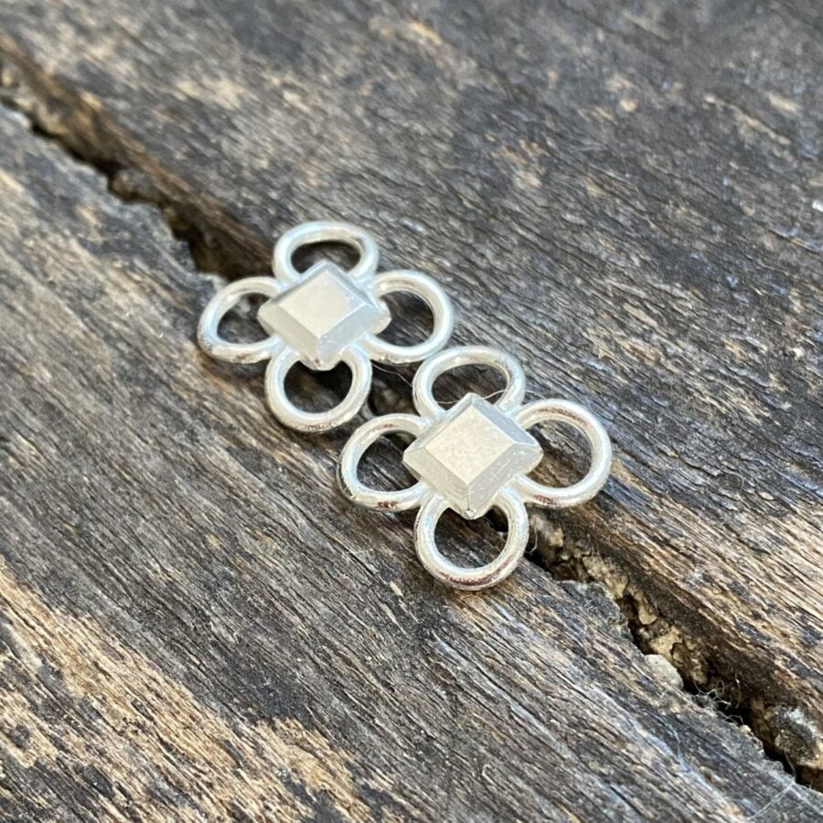 Silver quatrefoil earrings on a wooden background