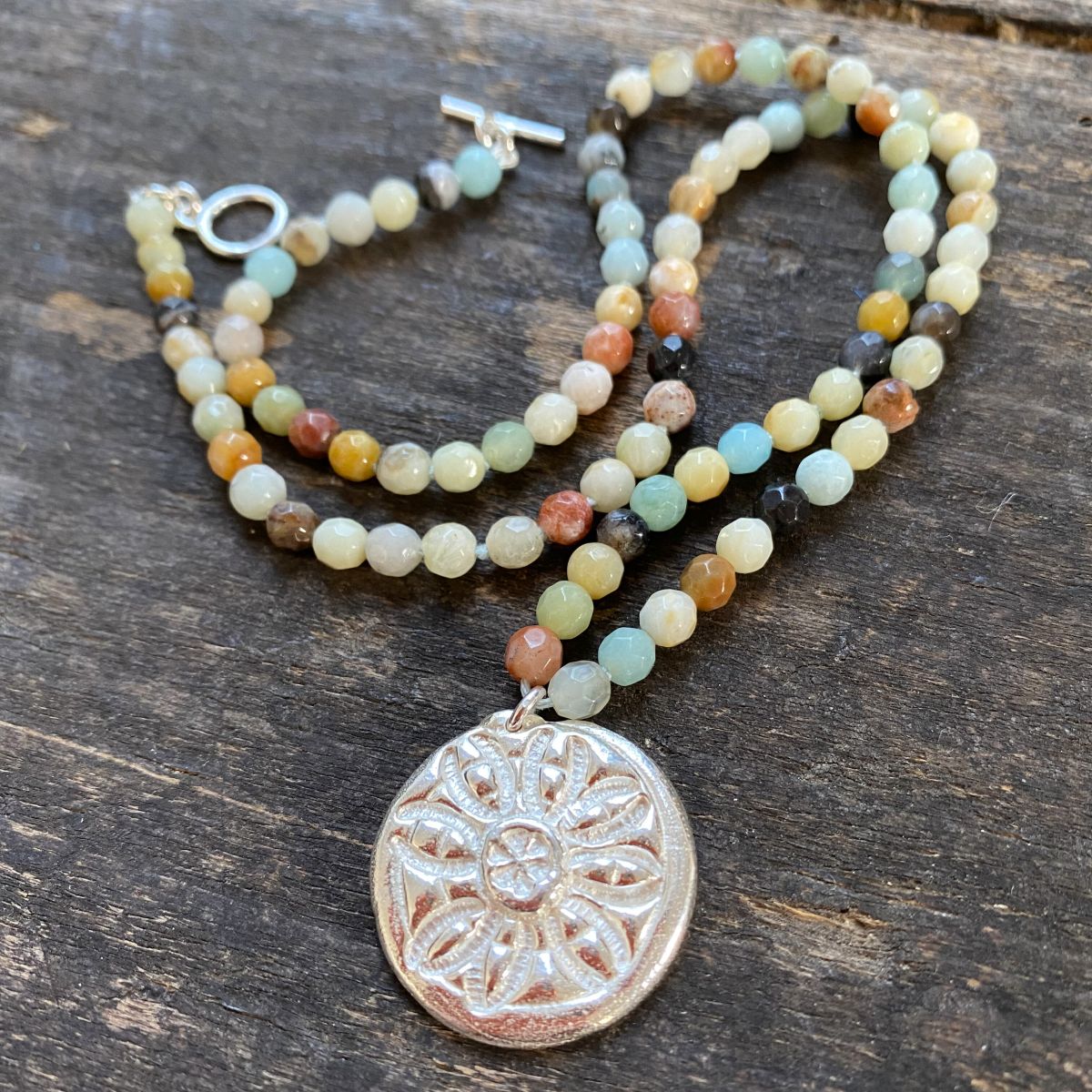 Silver and amazonite necklace by Clare de la Torre on a wooden background