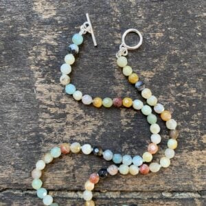 Silver and amazonite necklace by Clare de la Torre on a wooden background