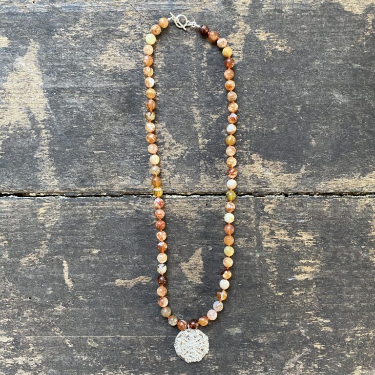 Brandy opal gemstone necklace by Clare de la Torre on a wooden background