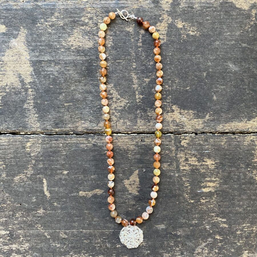 Brandy opal gemstone necklace by Clare de la Torre on a wooden background