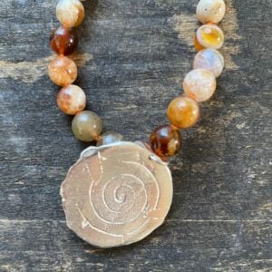 Brandy opal gemstone necklace by Clare de la Torre on a wooden background