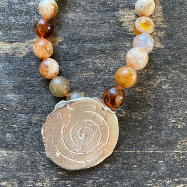 Brandy opal gemstone necklace by Clare de la Torre on a wooden background