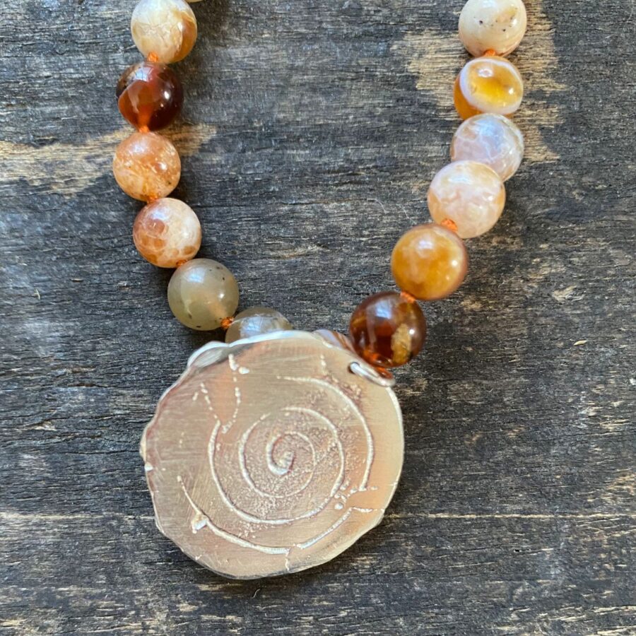 Brandy opal gemstone necklace by Clare de la Torre on a wooden background