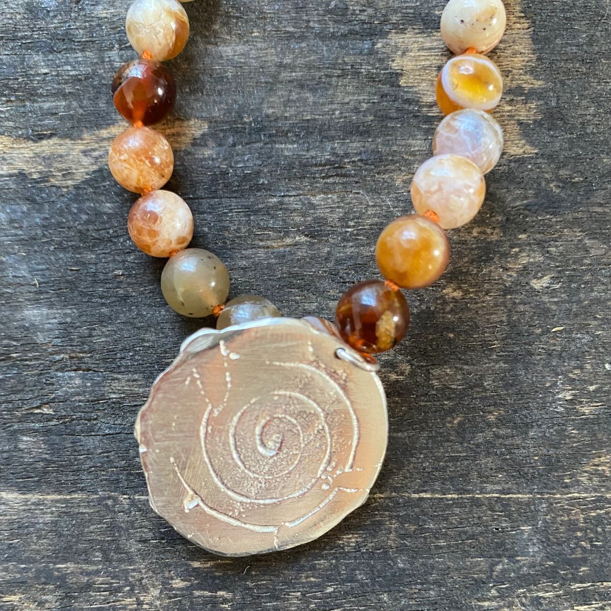 Brandy opal gemstone necklace by Clare de la Torre on a wooden background