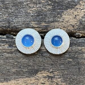 Silver cog earrings with blue stone on a wooden background