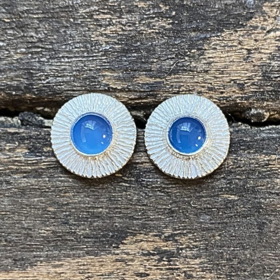 Silver cog earrings with blue stone on a wooden background