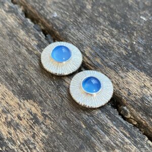 Silver cog earrings with blue stone on a wooden background