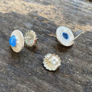 Silver cog earrings with blue stone on a wooden background