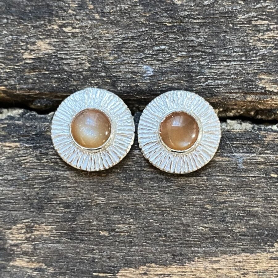 Silver cog earrings with moonstones on a wooden background