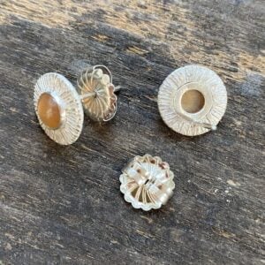 Silver cog earrings with moonstones on a wooden background