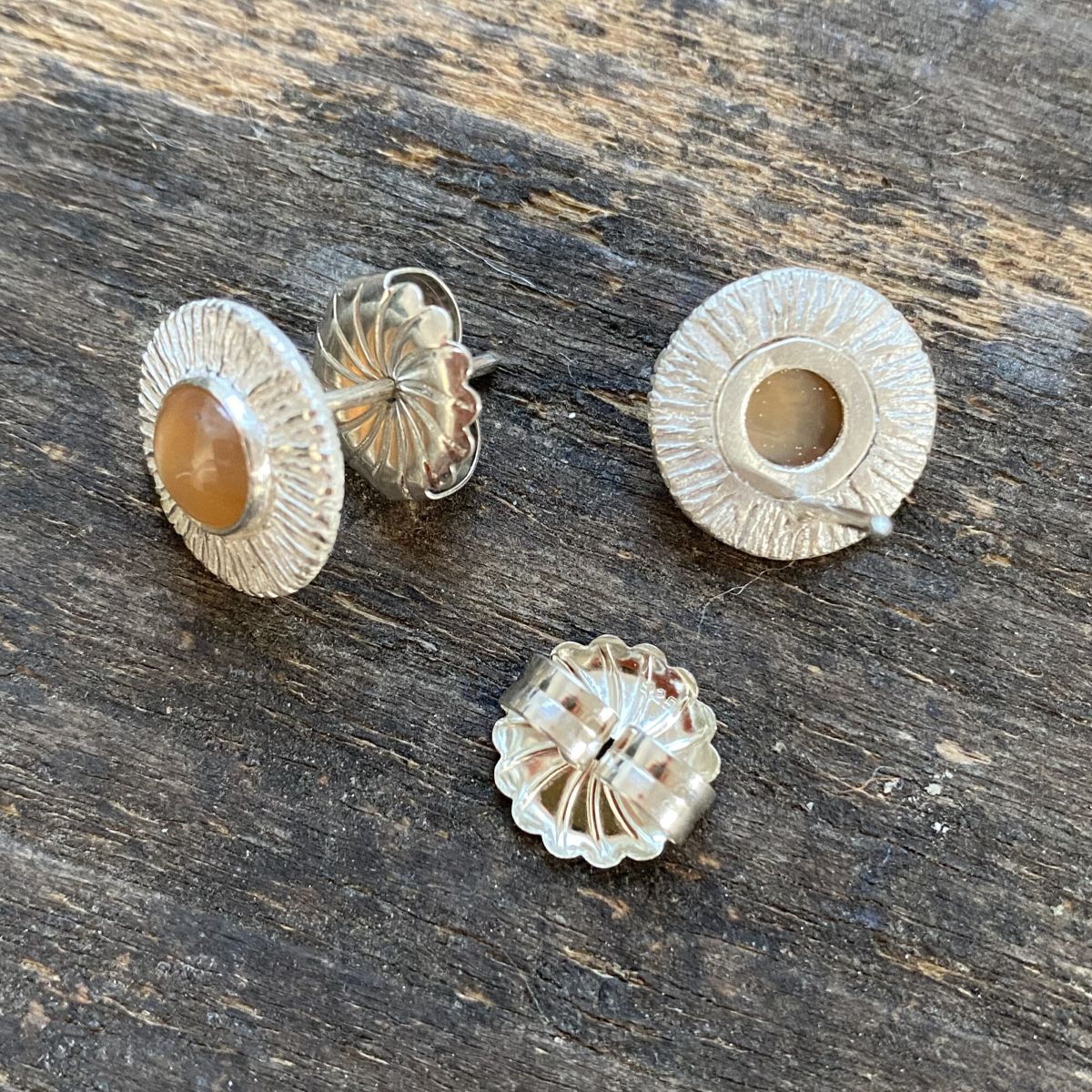 Silver cog earrings with moonstones on a wooden background