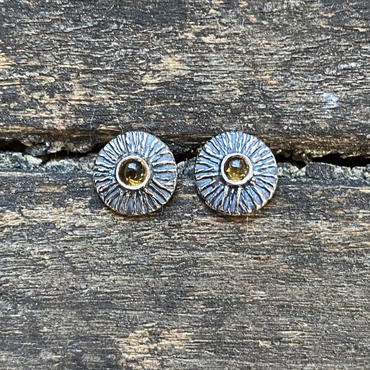 Silver disc earrings with citrine centre on a wooden background