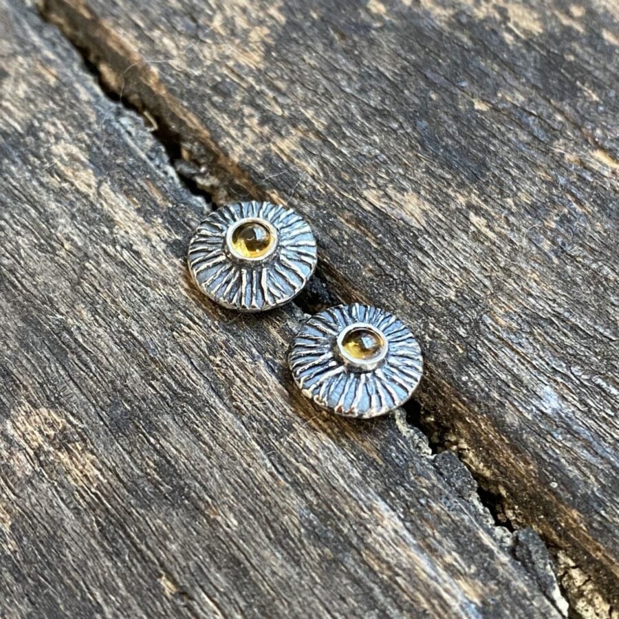 Silver disc earrings with citrine centre on a wooden background