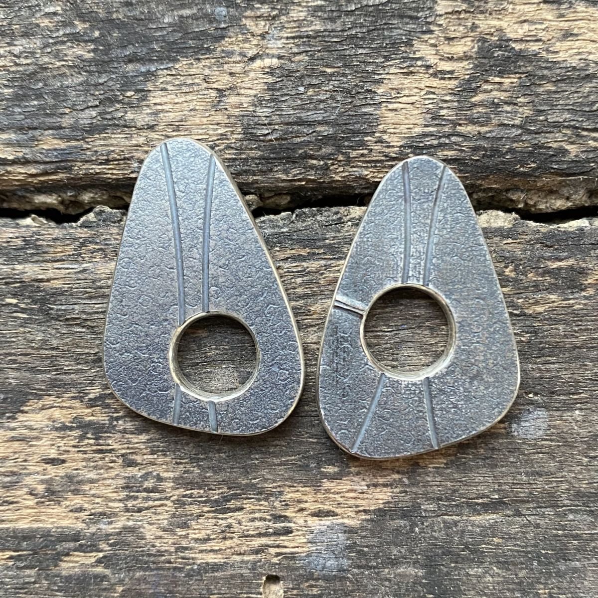 Silver earrings on wooden background