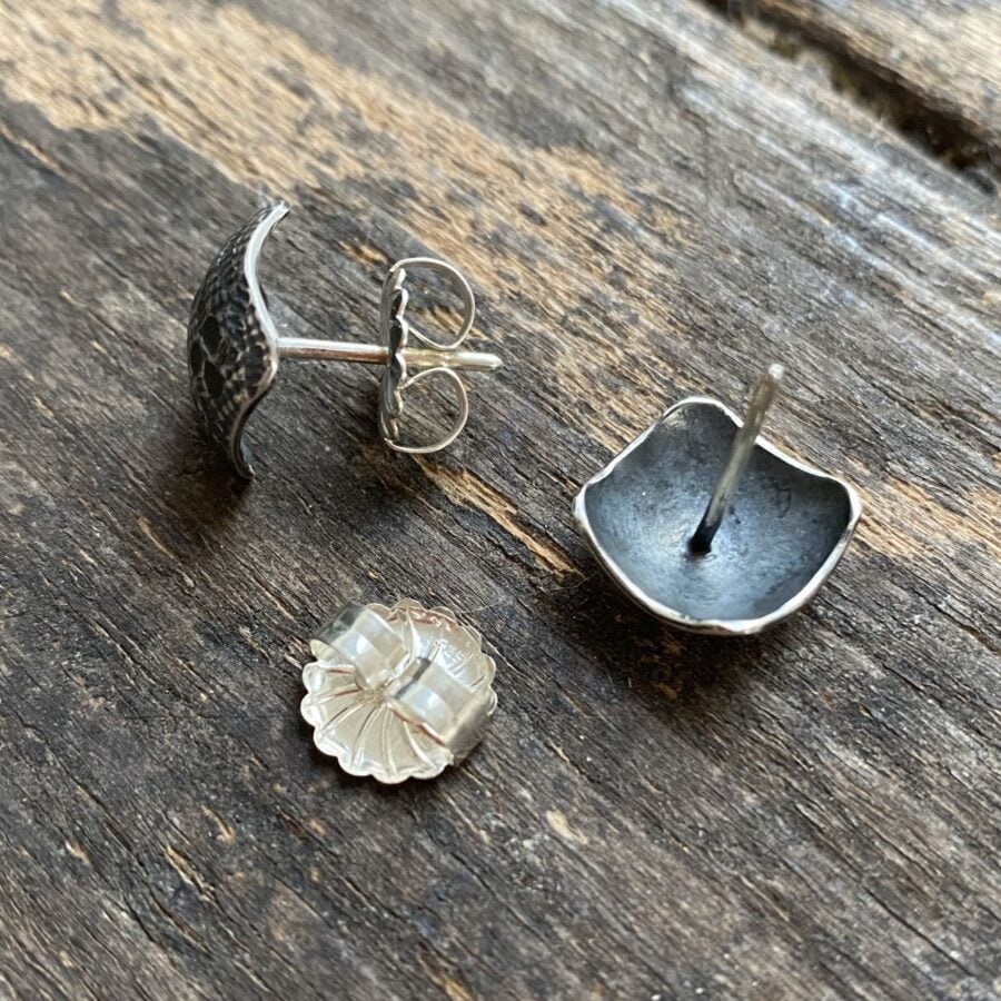 Silver earrings on wooden background