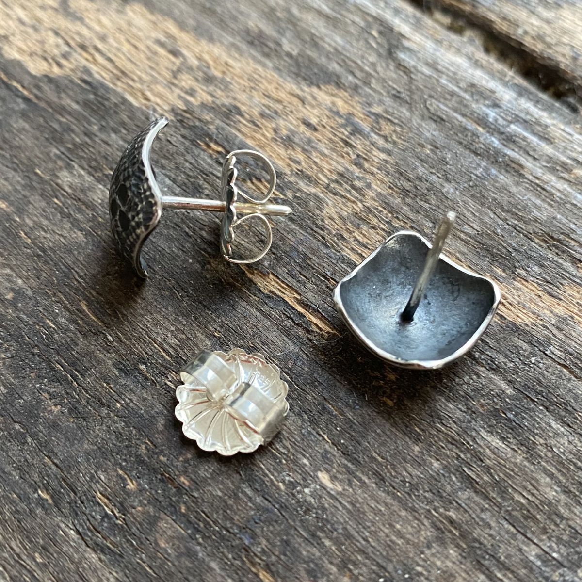 Silver earrings on wooden background