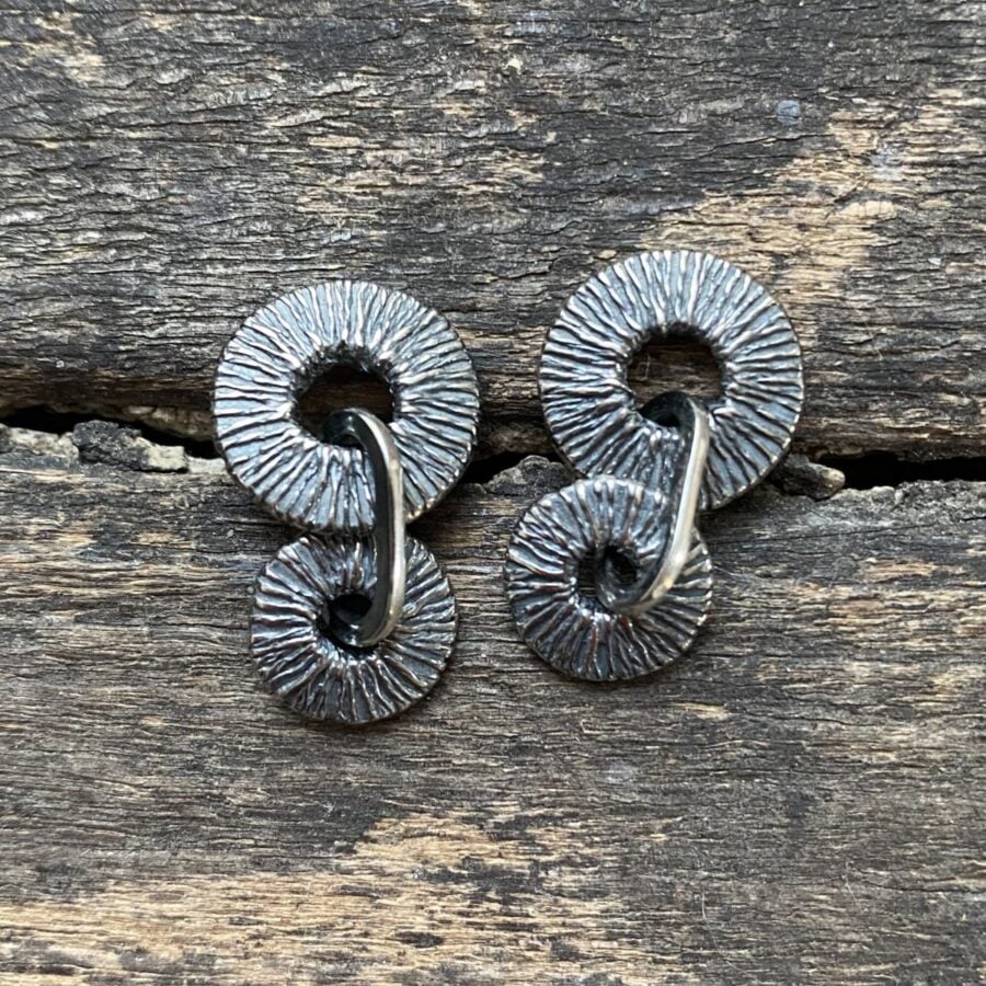 Silver earrings on wooden background