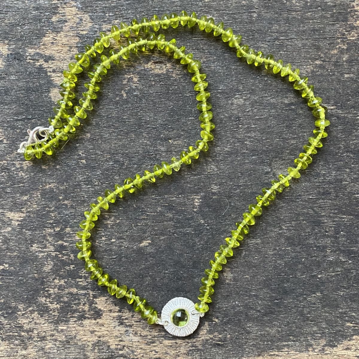 Peridot bead necklace on a wooden background