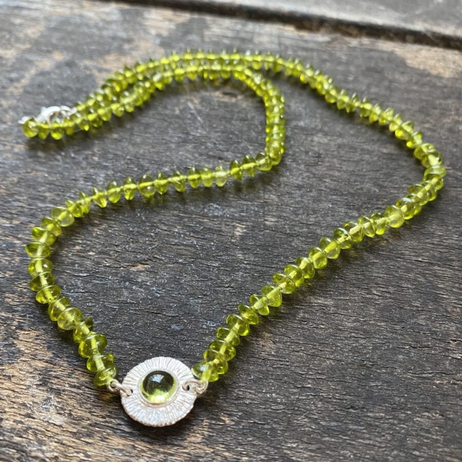 Peridot bead necklace on a wooden background