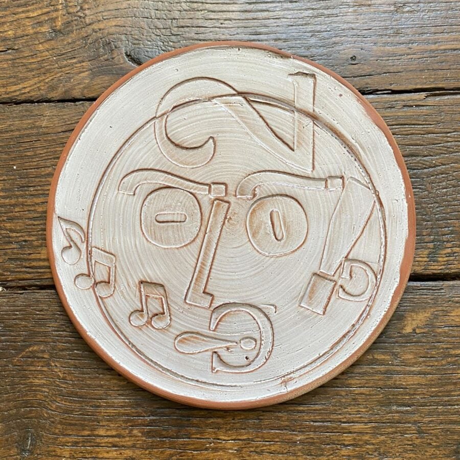 Round plate with letterpress blocks impressed into the clay to make a face. By John Ingledew.