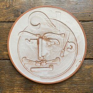 Round plate with letterpress blocks impressed into the clay to make a face. By John Ingledew.
