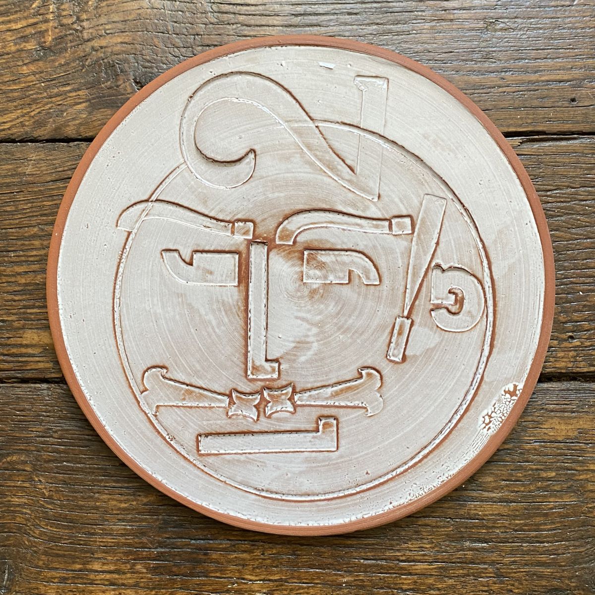 Round plate with letterpress blocks impressed into the clay to make a face. By John Ingledew.