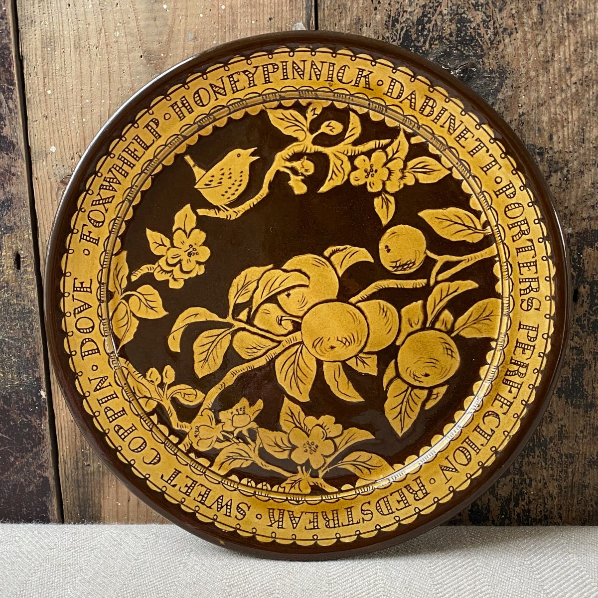 Katie B Morgan slipware Plate against a wooden panelled wall.
