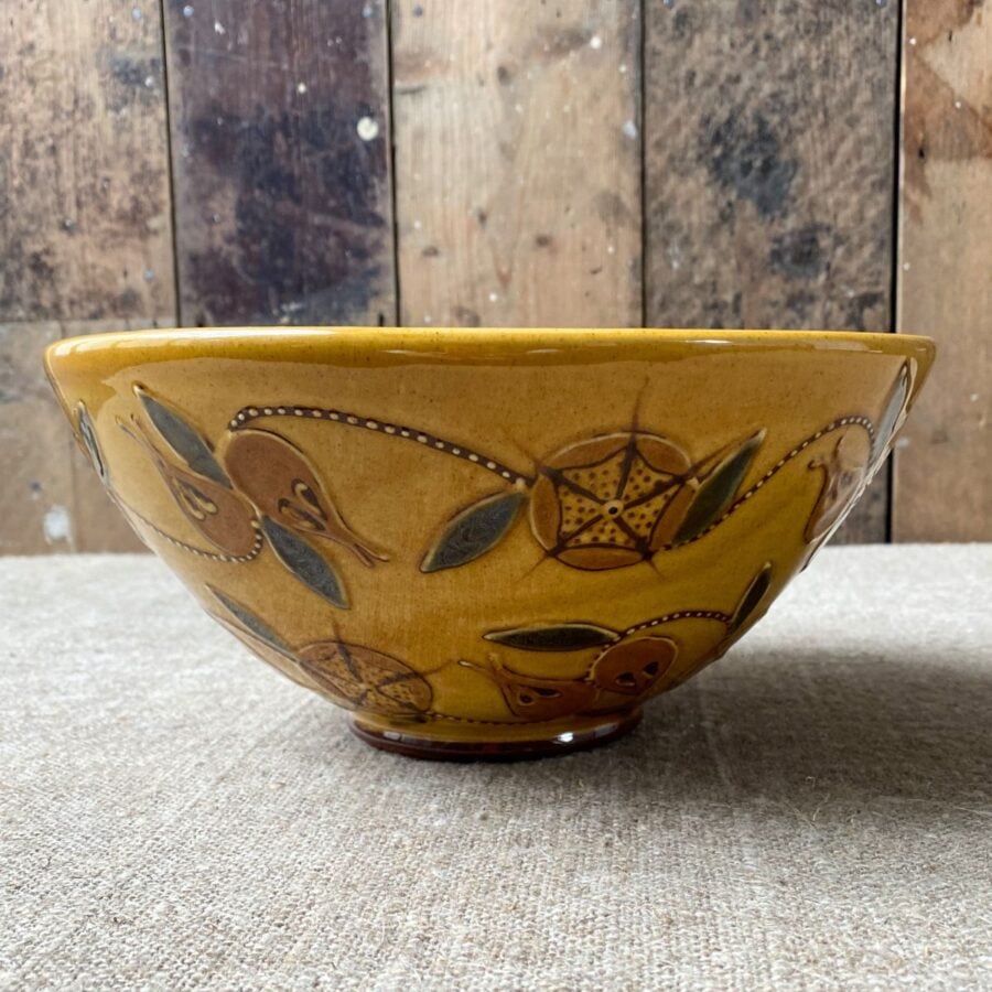 Side view of Carole Glover slipware bowl decorated with stylised medlar fruits