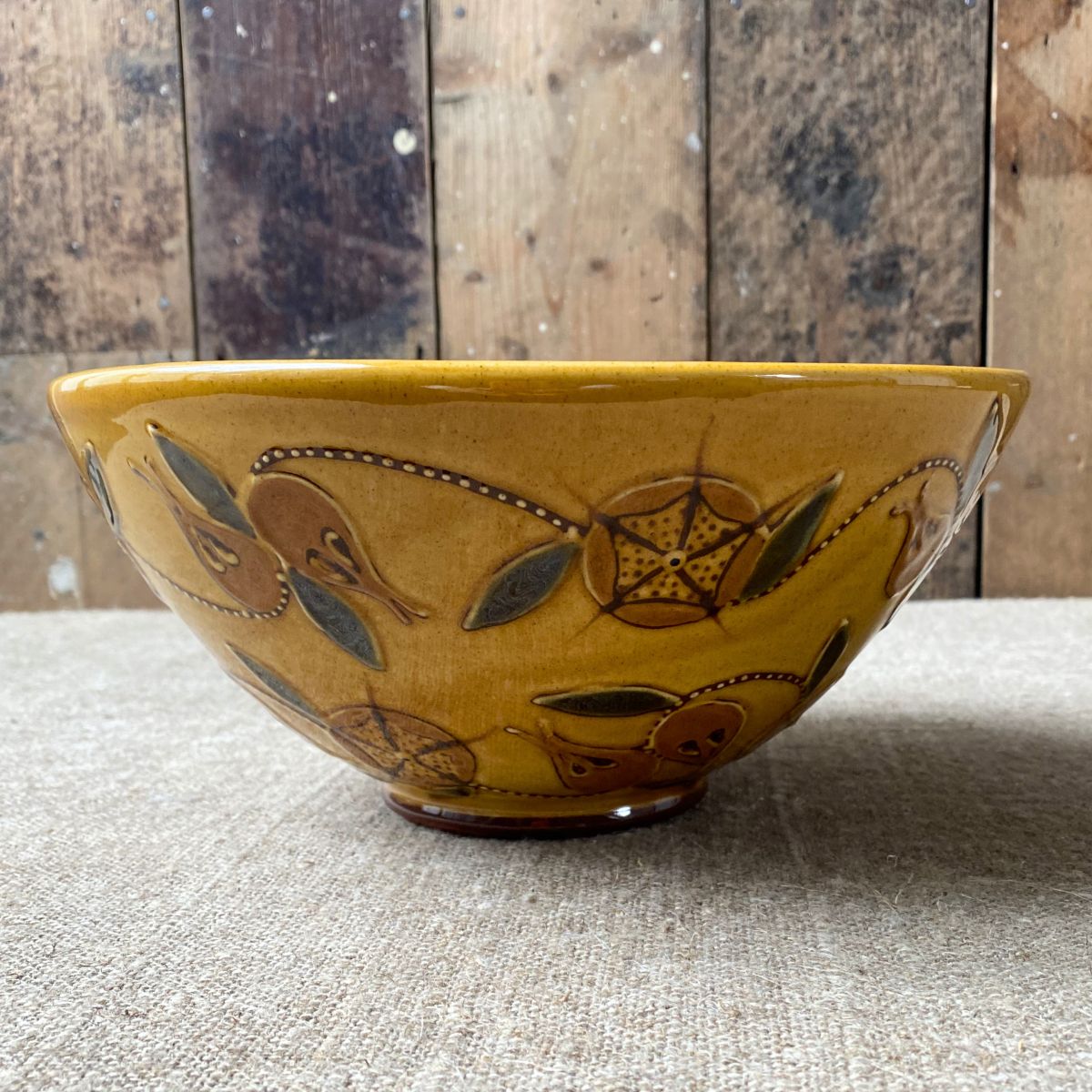 Side view of Carole Glover slipware bowl decorated with stylised medlar fruits