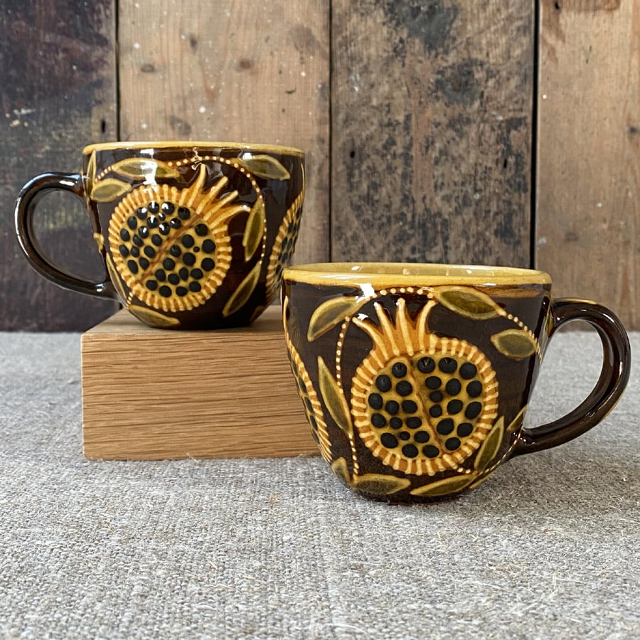 Pair of slipware mugs by Carole Glover on a linen cloth and a wooden background.