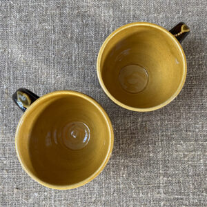 Pair of slipware mugs by Carole Glover from above, on a linen cloth