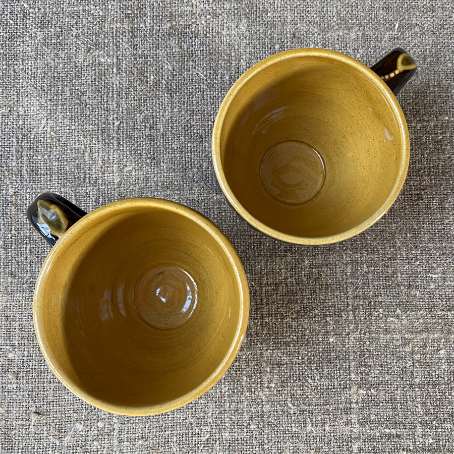 Pair of slipware mugs by Carole Glover from above, on a linen cloth